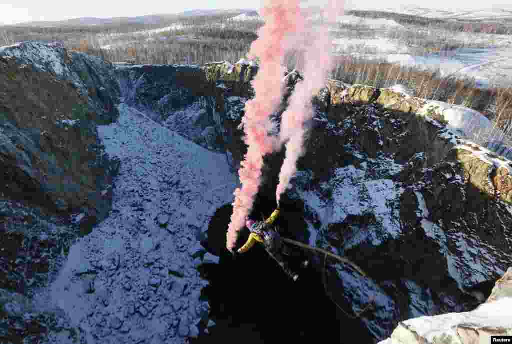 A member of the amateur rope-jumping group "Exit Point" takes a rope jump from a 120-meter (394 feet) high rock down to a man-made crater called "Tuimsky Proval" (Tuimsky Cavity), with the air temperature at about minus 15°C(5°F), outside the town of Tuim in Khakassia region, Russia, Oct. 18, 2014.