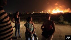 Vecinos de la refinería de Amuay, cerca de Punto Fijo, observan el fuego de la planta en el horizonte.