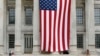 Two people sit on the steps of Brooklyn's Borough Hall where a huge American flag is displayed, July 3, 2014.
