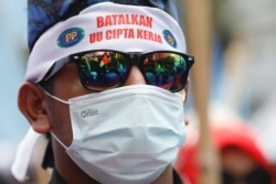 Seorang anggota serikat buruh mengenakan ikat kepala bertuliskan "batalkan UU Cipta Kerja" dalam demo saat Mahkamah Konstitusi membacakan putusan uji materi UU Cipta Kerja, di Jakarta, Senin, 25 November 2021. (Foto: Ajeng Dinar/Reuters)