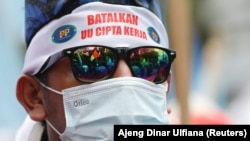 Seorang anggota serikat buruh mengenakan ikat kepala bertuliskan "batalkan UU Cipta Kerja" dalam demo memprotes perubahan aturan ketenagakerjaan saat Mahkamah Konstitusi membacakan putusan uji materi UU Cipta Kerja, di Jakarta, Senin, 25 November 2021. (F