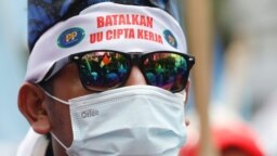 Seorang anggota serikat buruh mengenakan ikat kepala bertuliskan "Batalkan UU Cipta Kerja" dalam demo memprotes perubahan aturan ketenagakerjaan saat Mahkamah Konstitusi membacakan putusan uji materi UU Cipta Kerja, di Jakarta, Senin, 25 November 2021. 