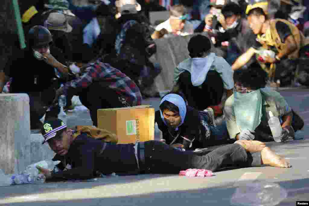 Anti-government protesters take cover during clashes with police near the Government house in Bangkok.
