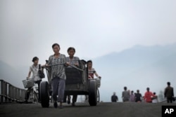 North Korean women push their cart and bicycles over a bridge in Hamhung, North Korea, July 21, 2017.