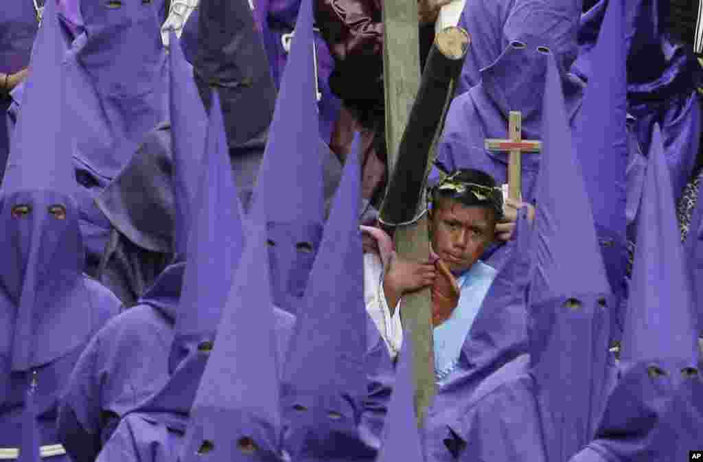 En Quito, Ecuador, un joven penitente carga una cruz de madera durante una procesión de Viernes Santo. Foto AP.