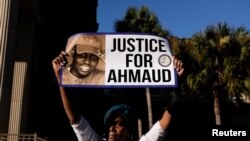 一位女士在佐治亞州的一個陪審團裁定三名被告謀殺阿莫德·阿貝里的罪名成立後，在法庭外高舉為阿莫德·阿貝里尋求正義的標語牌。(2021年11月24日)