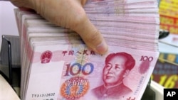 FILE - Teller counts Chinese yuan notes at a money exchange, Hong Kong.
