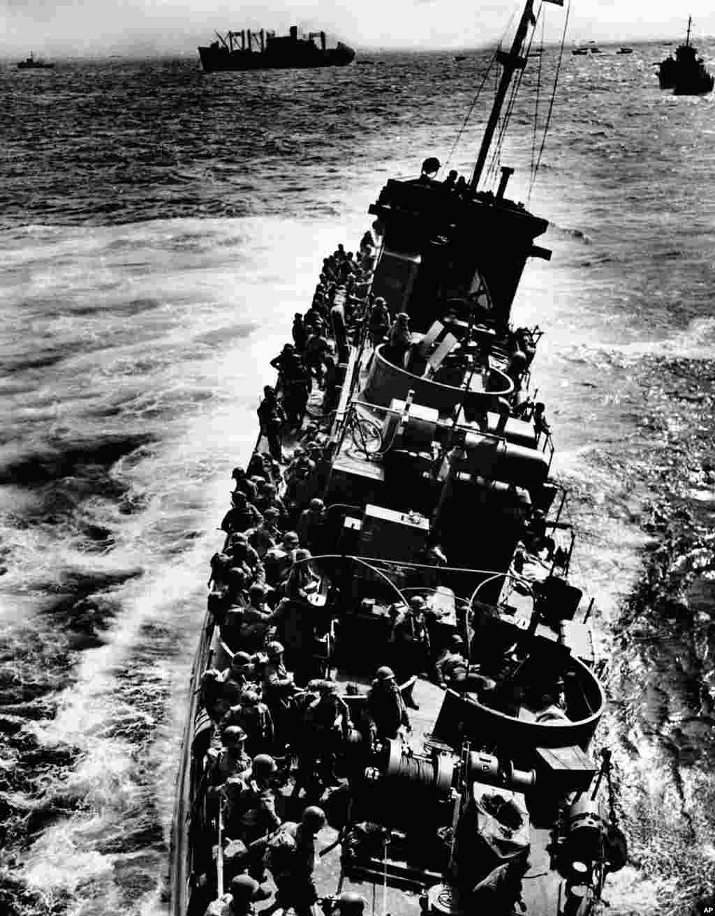 A Coast Guard LCI, listing to port, pulls alongside a transport ship to evacuate the troops and wounded just before the craft capsized and sank during the invasion of Normandy, France, June 6, 1944.&nbsp;