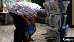 FILE - A man looks at newspapers on display in Algiers, Sept. 21, 2010.