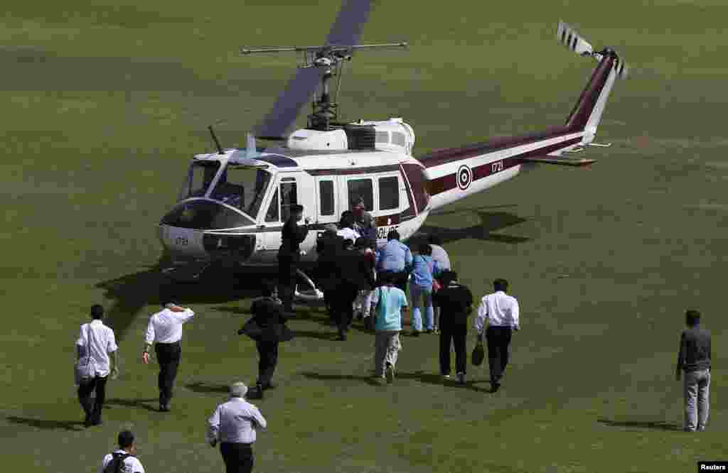 Police officers escort election commission officials to a helicopter at the Thai-Japan youth stadium in central Bangkok, Dec. 26, 2013. 