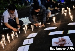 Sejumlah pengunjuk rasa menyalakan lilin dalam demo di depan istana kepresidenan untuk memprotes hukuman mati, Jakarta, 28 Juli 2016. (Foto: Bay Ismoyo/AFP)