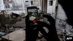 FILE - A Syrian gamer uses the Pokemon Go application on his mobile to catch a Pokemon amidst the rubble in the besieged rebel-controlled town of Douma, a flashpoint east of the capital Damascus, July 23, 2016.