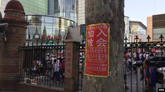 属于中国官方天主教爱国会系统的天津西开总堂在庭院贴出的招收新教徒的学习班通知，院外是喧嚣的商业区。（资料照）