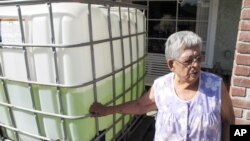 Vickie Yorba, 94, stands next to a water tank in front of her home in East Porterville, California, Sept. 15, 2014. Her water well is one of 290 in the area that ran dry in the state’s historic drought. (AP Photo/Scott Smith)