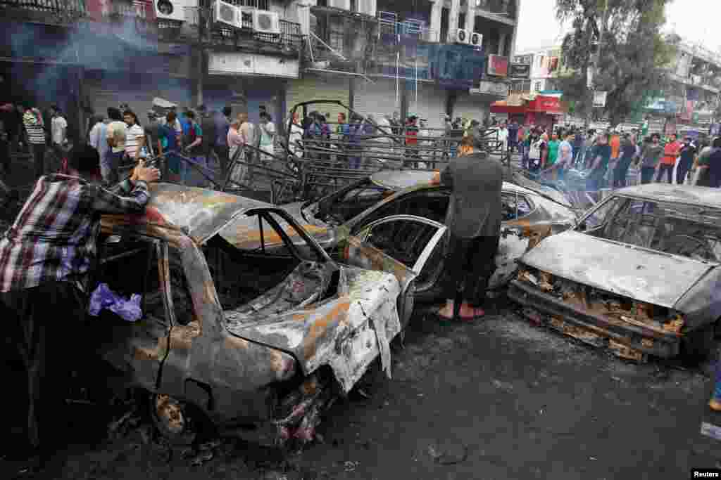 People inspect the site of a suicide car bomb in the Karrada shopping area, July 3, 2016.