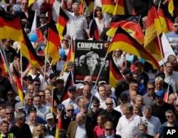 FILE - AfD supporters march with a poster showing German Chancellor Angela Merkel in Berlin, Germany, Sunday, May 27, 2018.