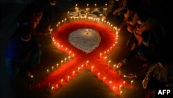 ILUSTRASI - Para sukarelawan bersama pekerja seks menyalakan lilin berbentuk pita merah pada malam peringatan 'Hari AIDS Sedunia' di Khalpara, Siliguri, 30 November 2021. (Diptendu DUTTA / AFP)