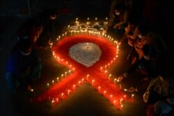 Relawan dan pekerja seks menyalakan lilin berbentuk pita merah pada malam peringatan 'Hari AIDS Sedunia' di kawasan Khalpara di Siliguri, 30 November 2021.(Diptendu DUTTA / AFP)
