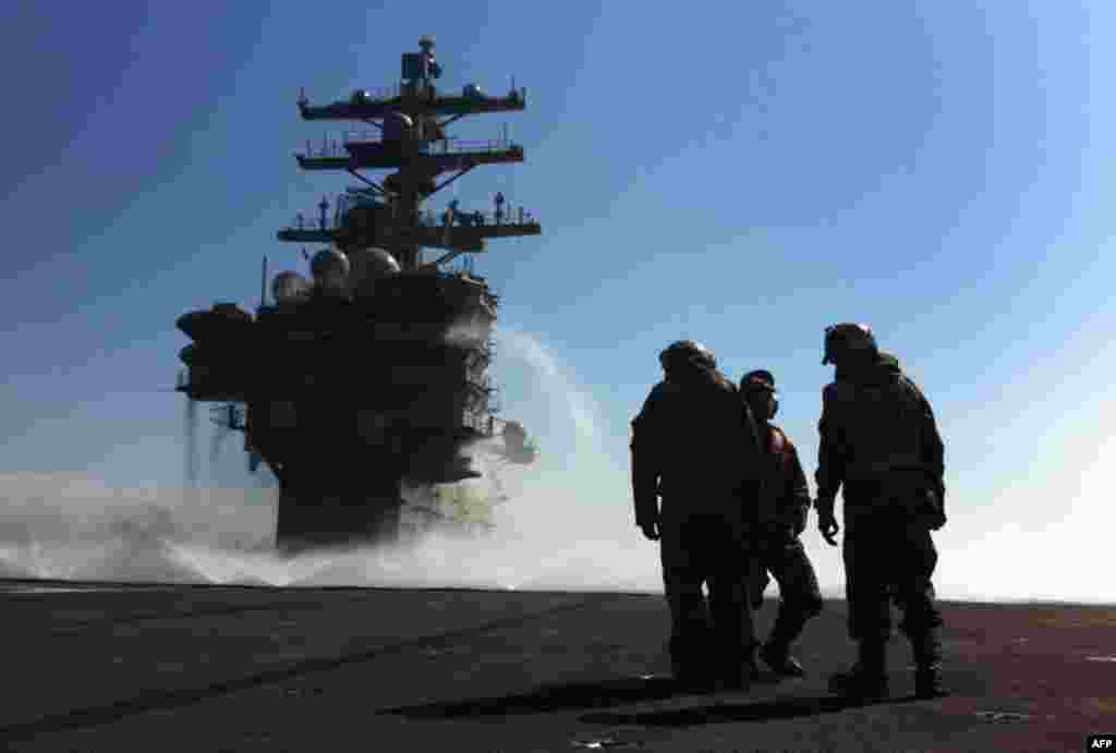 March 23: U.S. Navy deck crew stand near the island on the deck sprayed for radioactive decontamination aboard USS Ronald Reagan off the Japanese coast. (AP Photo/Eugene Hoshiko)