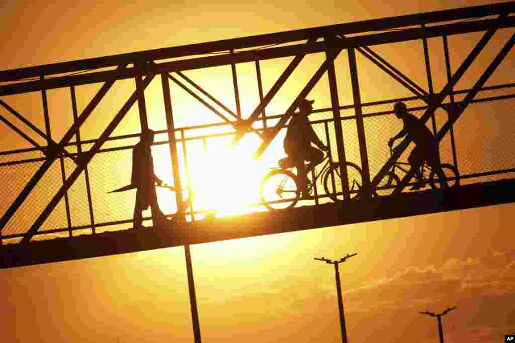 브라질 브라질리아에서 보행자와 자전거 타는 행인이 고속도로 위의 육교를 건고 있다.