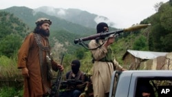 FILE - Pakistani Taliban patrol in then their stronghold of Shawal in Pakistani tribal region of South Waziristan, Aug. 5, 2012. 