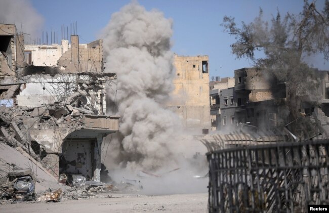 FILE - Smoke rises after a landmine is exploded as fighters of Syrian Democratic Forces clear roads in Raqqa, Syria, Oct. 18, 2017.