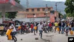 Orang-orang berlari mencari perlindungan saat polisi melayangkan tembakan peringatan ke udara dalam upaya membubarkan massa yang hendak membakar sebuah pom bensin di Port-au-Prince Haiti, pada 23 Oktober 2021. (Foto: AP/Matias Delacroix)