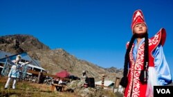 At the Chui Oozi cultural center, a young woman shows off traditional native dress. In the background, Bolot Byiryshev, one of Altai’s most accomplished throat singers, rests after singing an epic ballad (V. Undritz/VOA).