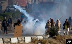 A protester hurls back a tear gas shell fired by police during a clash in Islamabad, Pakistan, Nov. 25, 2017.