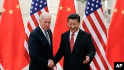 Chinese President Xi Jinping, right, shakes hands with U.S Vice President Joe Biden, left, as they pose for photos at the Great Hall of the People in Beijing, Dec. 4, 2013. 
