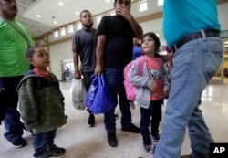FILE - A group of immigrants from Honduras and Guatemala seeking asylum receive help the bus station after they were processed and released by U.S. Customs and Border Protection, June 21, 2018, in McAllen, Texas.