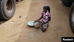 A girl gathers rice spilled from a humanitarian food convoy that arrived from the Malian capital Bamako in the northeastern city of Gao, Jun. 14, 2012. 