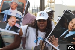 A young woman holds up pictures of Abdoulaye Wade and his son Karim as she waits for the former President at Dakar international airport, Dakar, Senegal, July 10, 2017. (S. Christensen/VOA)