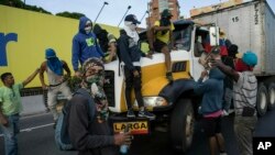 Anti-government protesters stop a truck while blocking a highway with a small group of demonstrators who were returning from a peaceful demonstration called by self-declared interim president Juan Guaido to demand the resignation of President Nicolas Madu