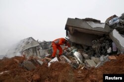 A firefighter uses a flashlight to search for survivors among the debris of collapsed buildings after a landslide hit an industrial park in Shenzhen, Guangzhou, China, Dec. 20, 2015.