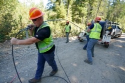 Workers install broadband internet service to homes in a rural area around Lake Christine near Belfair, Washington State, August 4, 2021.