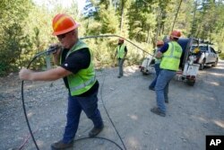 Workers install broadband internet service to homes in a rural area around Lake Christine near Belfair, Washington State, August 4, 2021.