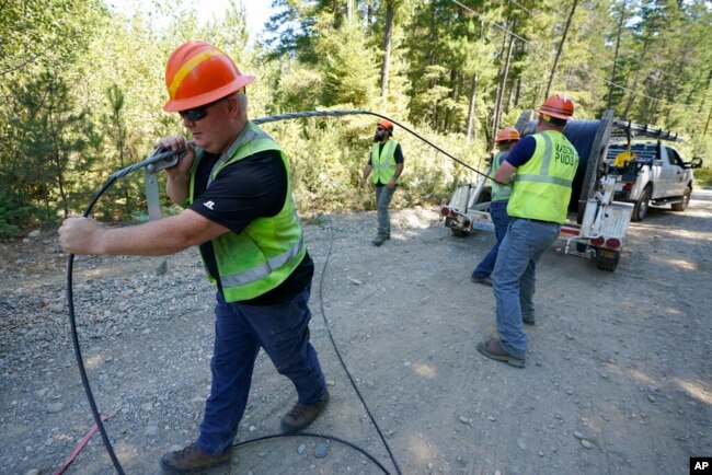 Workers install broadband internet service to homes in a rural area around Lake Christine near Belfair, Washington State, August 4, 2021.