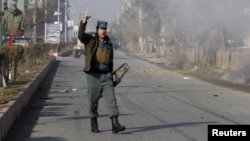 An Afghan policeman reacts as smoke billows during an attack near the Pakistani consulate in Jalalabad, Afghanistan, Jan. 13, 2016. 