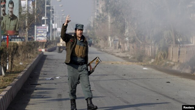 Un policía afgano reacciona al humo que sale del ataque al consulado pakistaní en Jalalabad, Afganistán, el miércoles, 13 de enero de 2016.