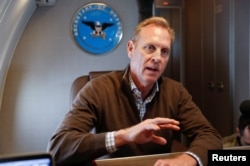 FILE - Acting Secretary of Defense Patrick Shanahan gestures while speaking to members of the media aboard a military plane prior to his arrival at Andrews Air Force Base, Maryland, Feb. 23, 2019.