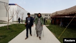 Rahmatullah Amiri, right, a political science student of American University of Afghanistan who was injured in last year's attack, arrives for new orientation sessions at a American University in Kabul, Afghanistan, March 27, 2017.