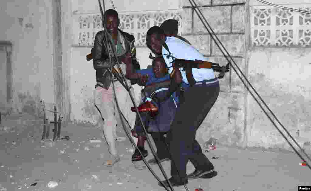 Police officers carry an injured man from the scene of a bomb attack outside the Jazeera Hotel in Mogadishu, Jan. 1, 2014.