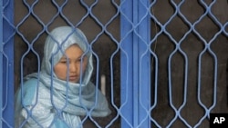 An Afghan inmate watches from behind a barred window during a media event at a women's prison in Kabul. (File Photo - March 30, 2010)