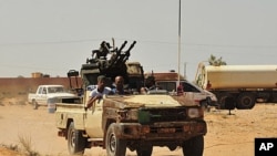 Anti-Gadhafi fighters ride a pick-up truck with an anti-aircraft gun attached to it toward Sirte, September 10, 2011
