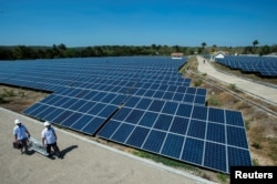 State Electricity Company officials walk near solar cell panels at the largest solar power plant in Indonesia, at Oelpuah village in Kupang, July 20, 2017 in this photo taken by Antara Foto.