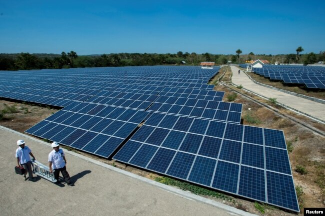 State Electricity Company officials walk near solar cell panels at the largest solar power plant in Indonesia, at Oelpuah village in Kupang, July 20, 2017 in this photo taken by Antara Foto.