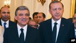 In this Aug. 12, 2014 photo, released by Turkish officials, Turkish President Abdullah Gul, left, and president-elect Recep Tayyip Erdogan stand pose for photos during a farewell reception for Gul in Ankara, Turkey.