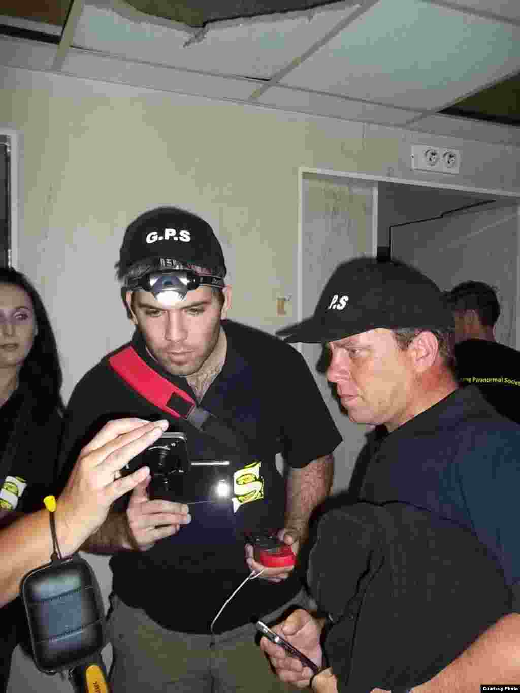 Paranormal investigators examine photographs they’ve taken for evidence of a ghost. They believe the Pretoria bar was haunted by a man who died in a fight over a game of pool. (Photo Courtesy the Gauteng Paranormal Society)