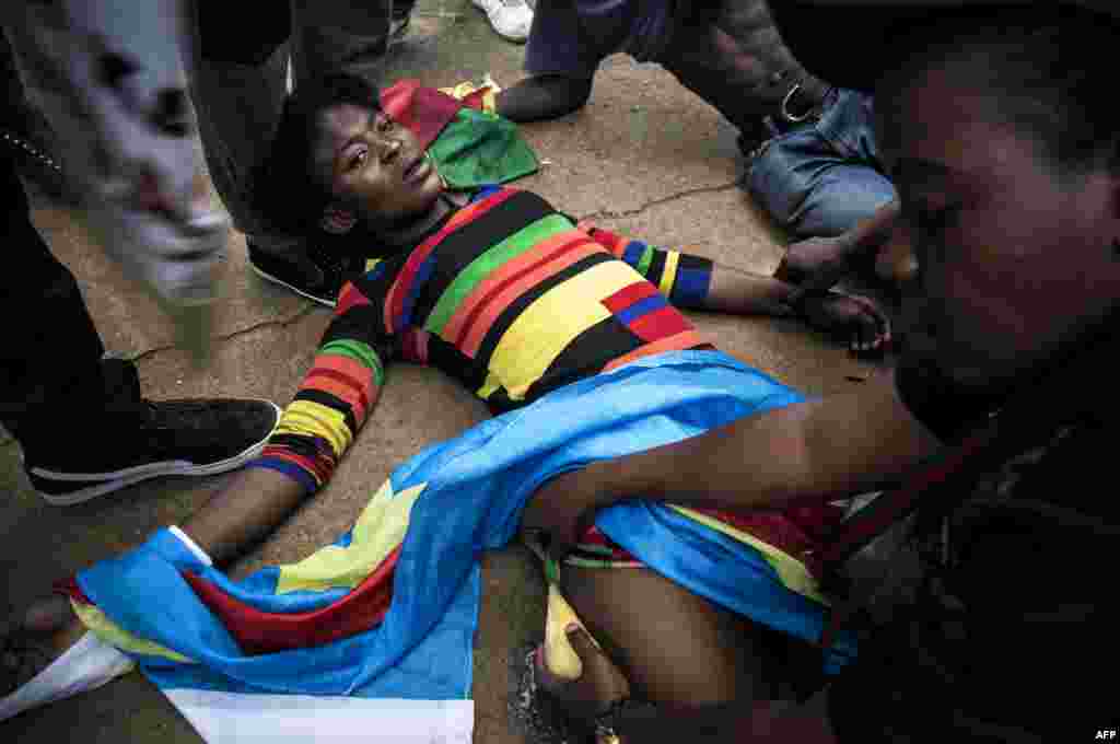 Seorang demonstran perempuan Kongo tergeletak setelah polisi menembaki demonstran dengan peluru karet dalam aksi protes anti pemerintah di depan Kedutaan Kongo (DRC) di Pretoria, Afrika Selatan.